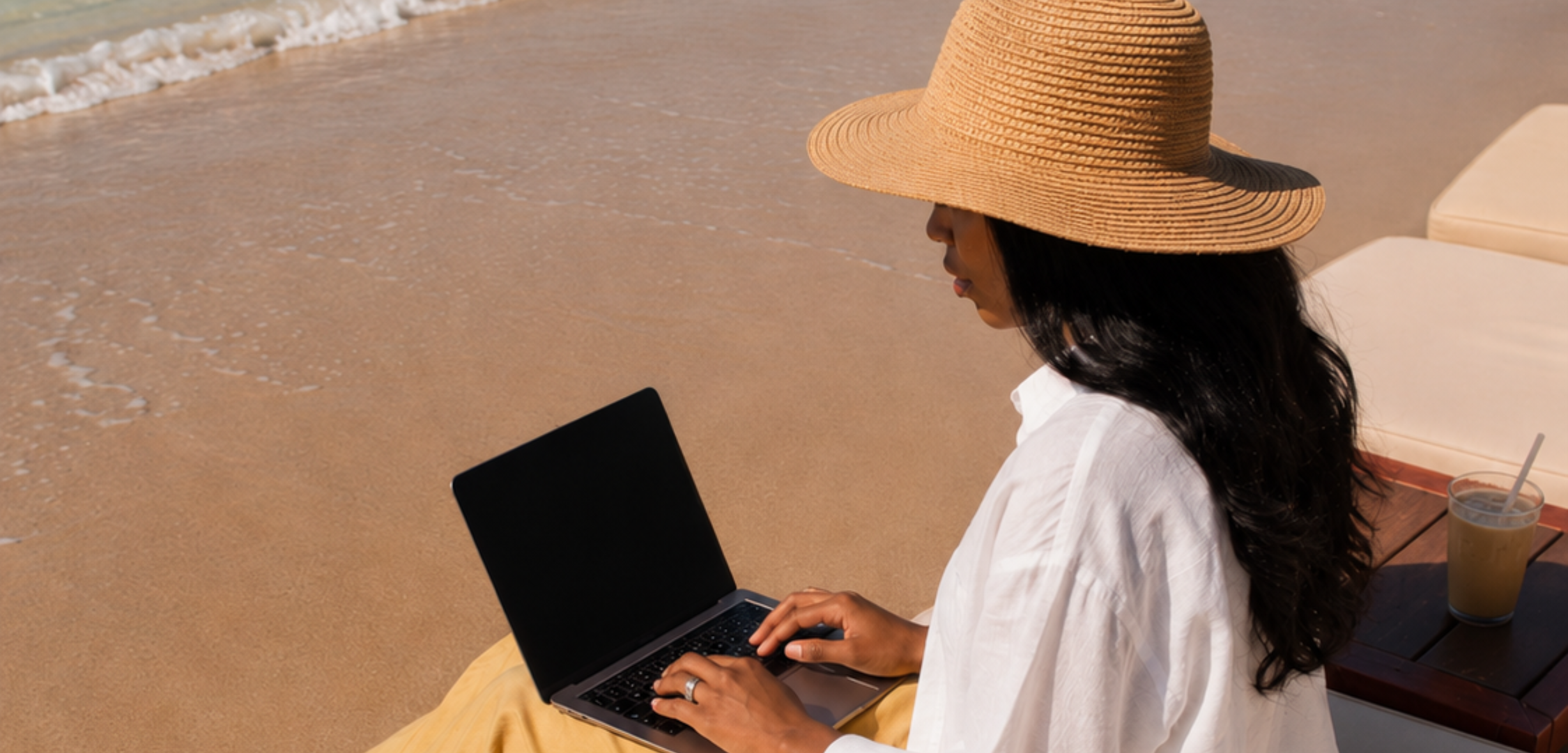 woman sitting on beach with laptop